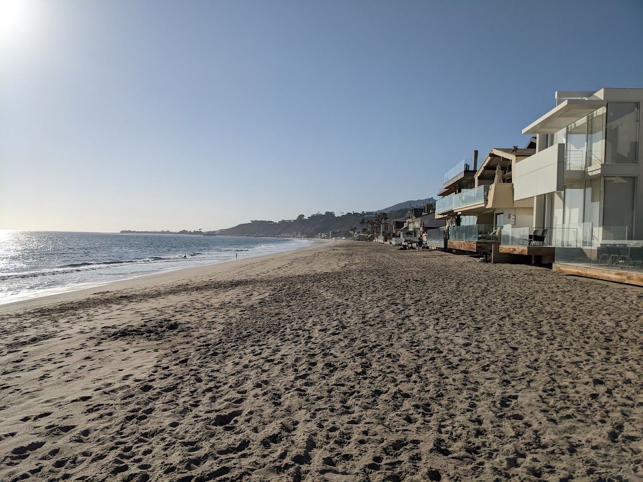 Narrow sand of Carbon Beach in Malibu with oceanfront houses and the Pacific at high tide