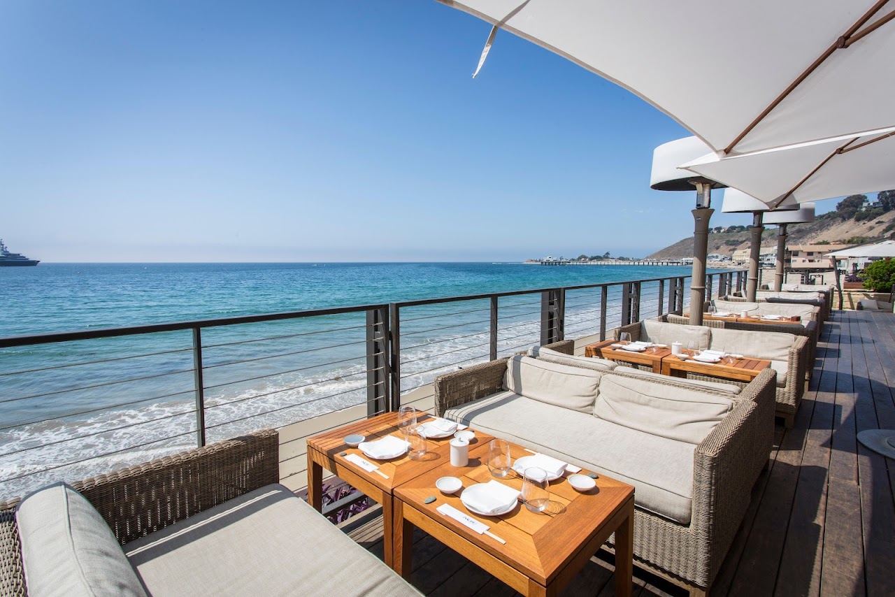 Teak dining deck of Nobu Malibu projecting over the sand of Carbon Beach toward the Pacific