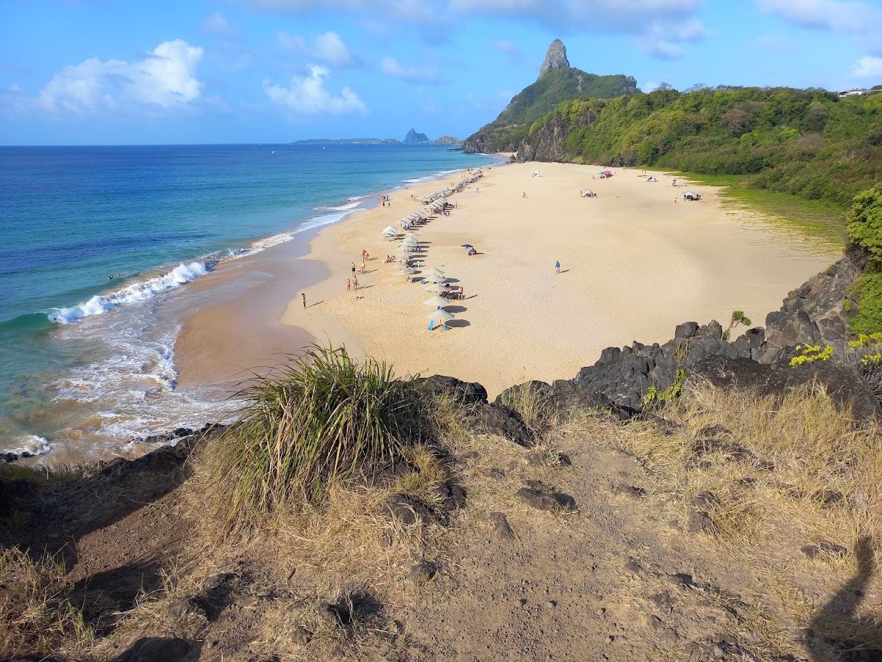 Clear inner sea water and wild sand backed by cliff at Praia do Bode in Fernando de Noronha
