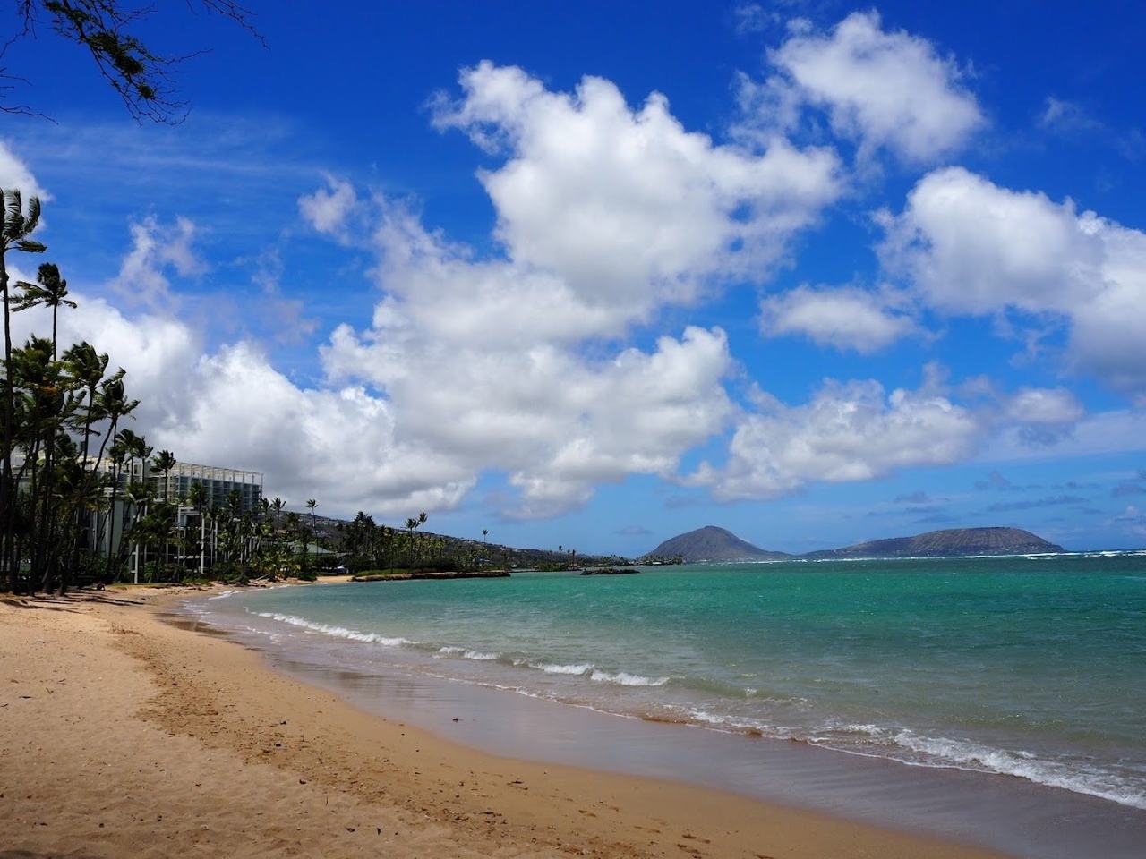 The narrow pale sand and calm reef flat at Kahala Beach in east Honolulu