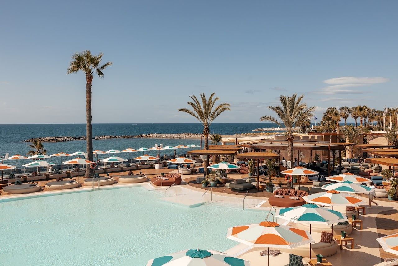 Poolside loungers and umbrellas on the white deck of Ocean Club Marbella