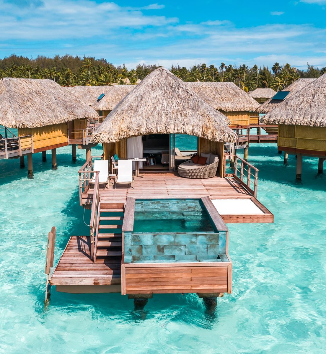 Overwater bungalows above a vivid blue lagoon beneath a green volcanic peak in Bora Bora