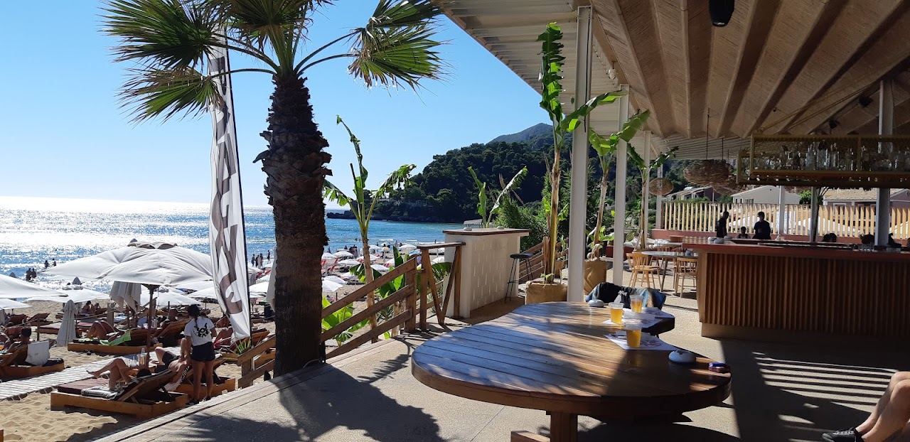 Sunbeds and umbrellas at Pazuzu on Glyfada beach in Corfu with the west facing Ionian horizon beyond