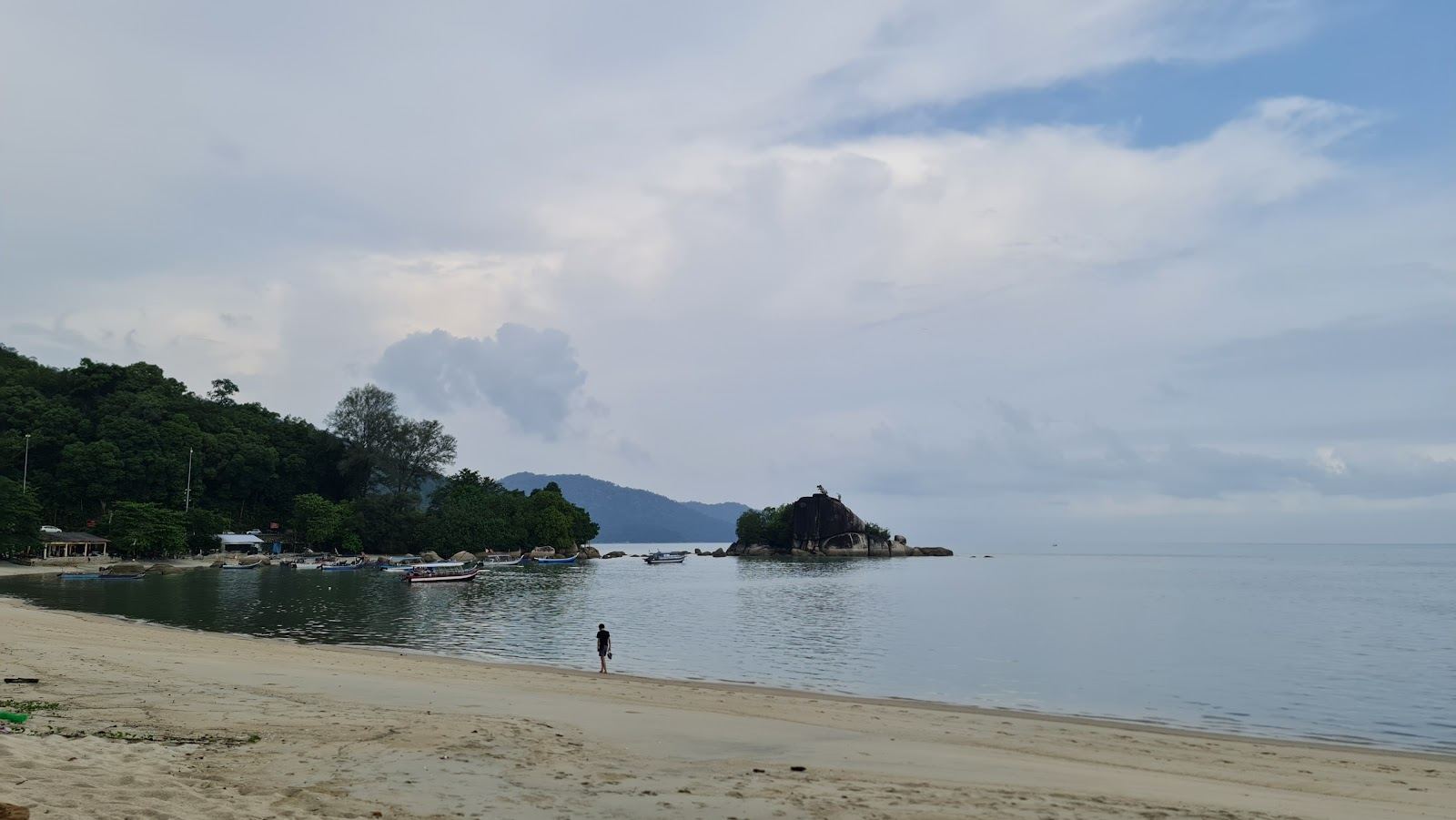 The long free beach at Batu Ferringhi on the north coast of Penang Malaysia with palms and calm sea