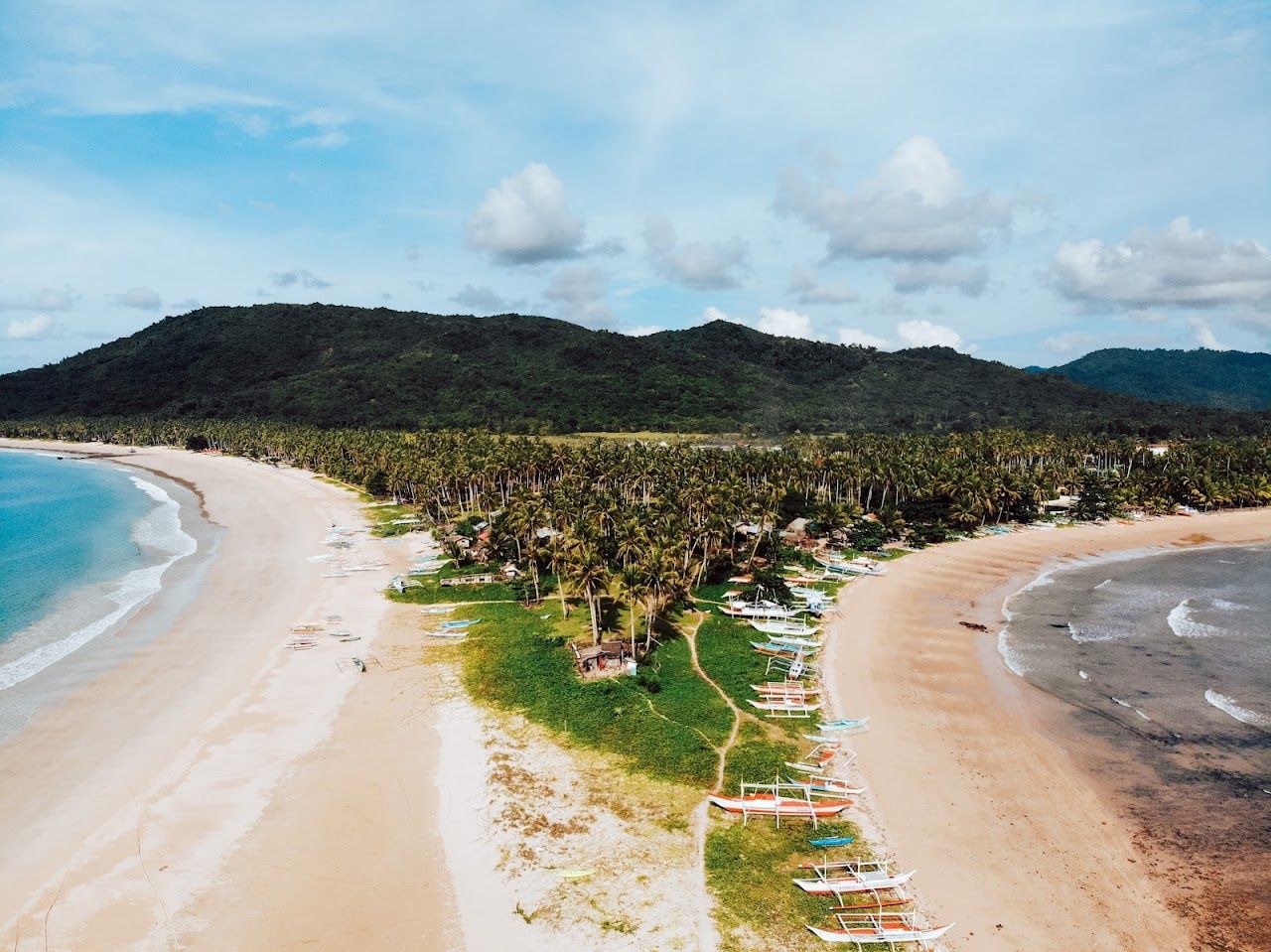The long curve of golden sand and clear water at Nacpan Beach near El Nido in Palawan