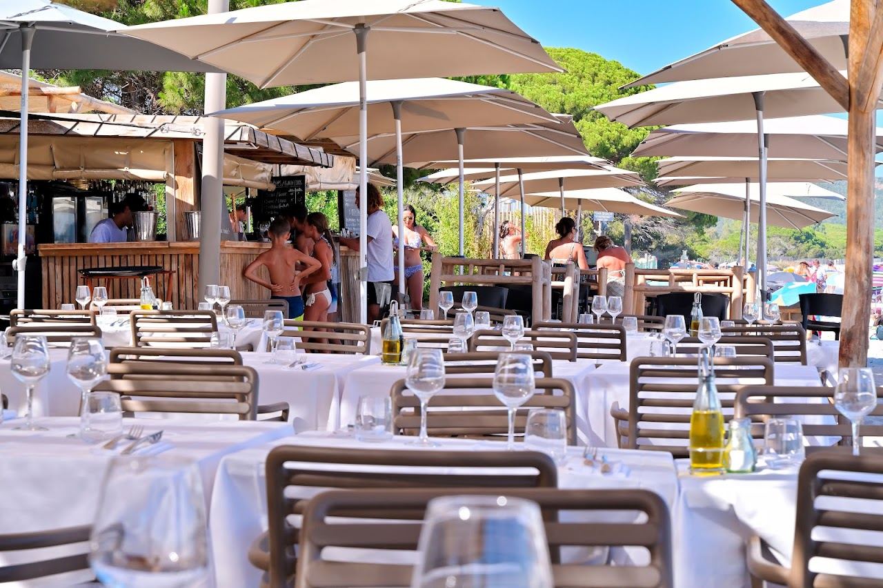 The wooden terrace and dining tables of Playa Baggia beach restaurant on the Tamaricciu stretch of Palombaggia bay, Corsica