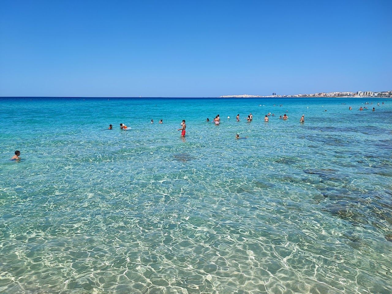 Shallow clear water and pale sand along the Baia Verde strip south of Gallipoli