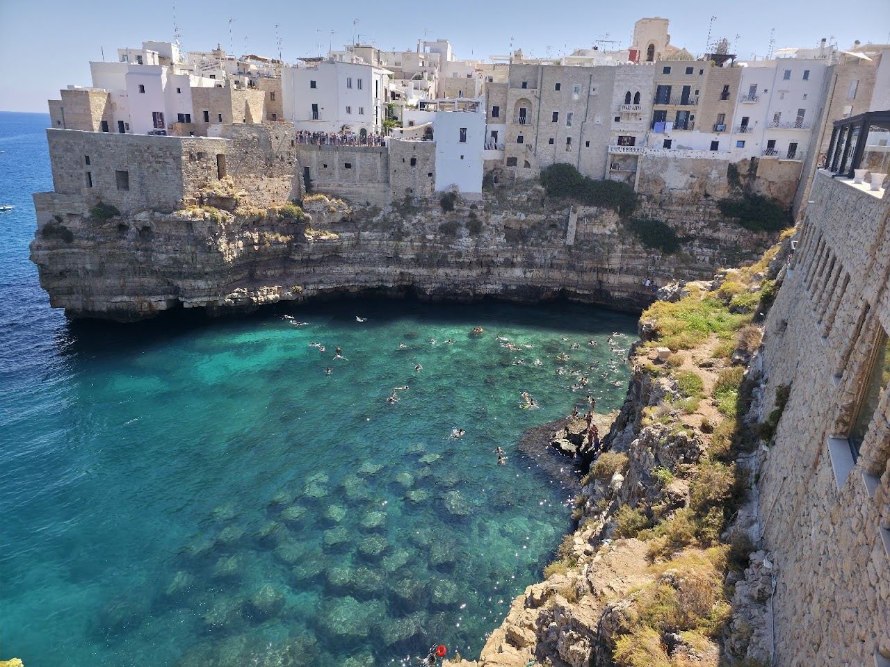 The cliff framed cove of Lama Monachile at Polignano a Mare glowing at golden hour in Puglia