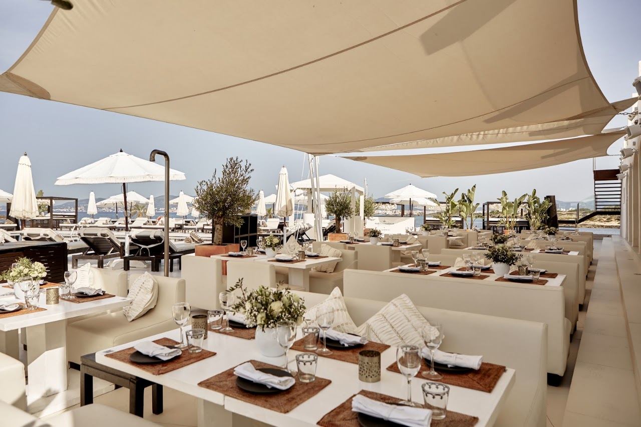 White loungers and the lava stone pool of Purobeach Palma on its promontory above the Bay of Palma