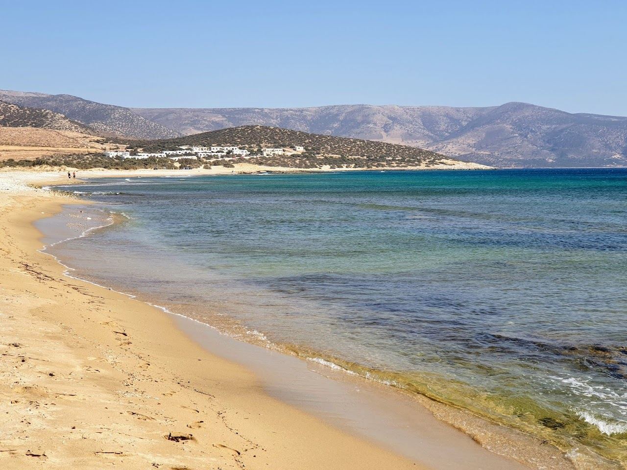 Soft sand and calm clear water backed by tamarisk trees at Pyrgaki beach in Naxos