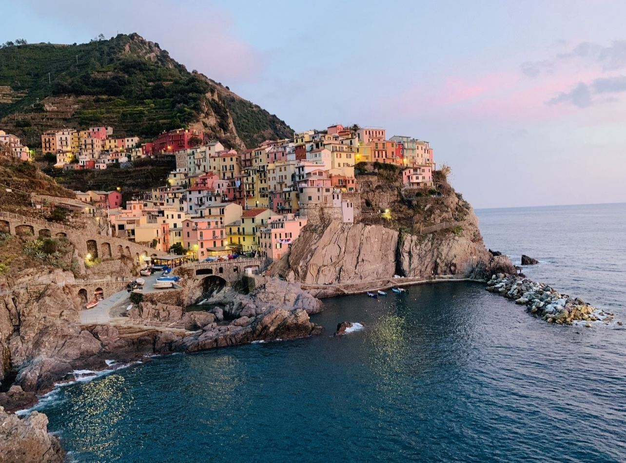 The steep pastel houses of Riomaggiore above its small rocky harbour in the Cinque Terre