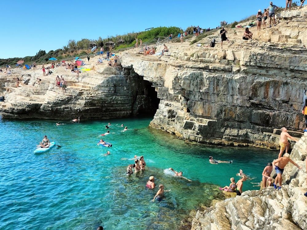 Swimmers and white rock ledges at the Mala Kolombarica cove below Safari Bar