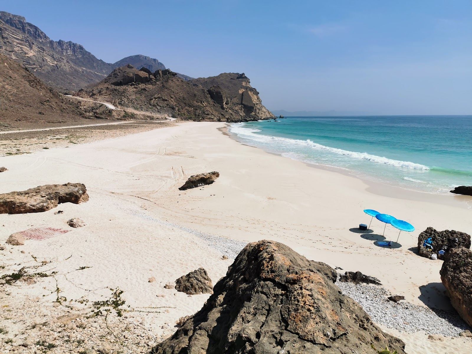 Secluded turquoise water and pale sand below green hills on the Dhofar coast near Salalah