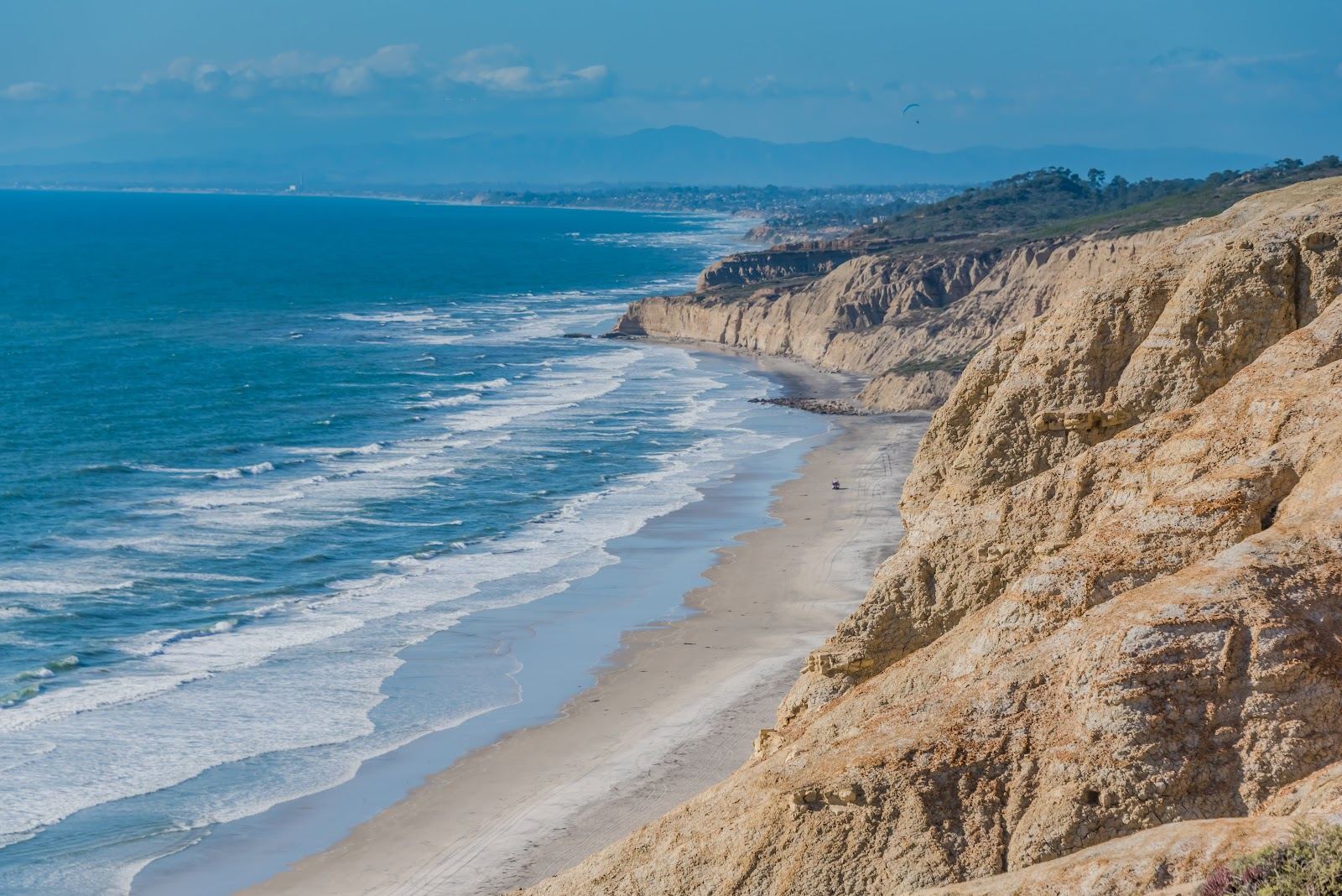 Wild empty sand below tall sandstone cliffs at a secluded San Diego beach