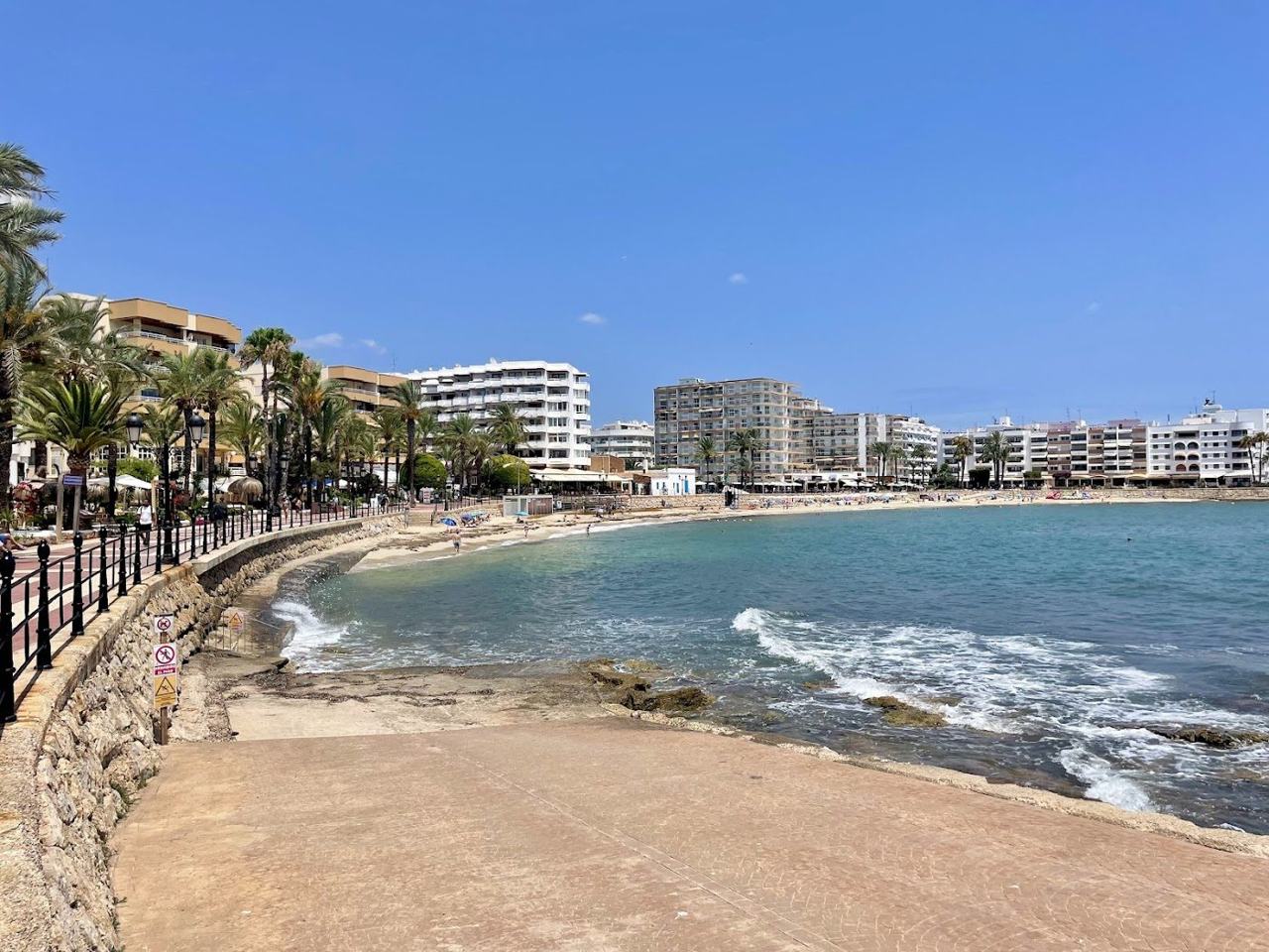 The fine white sand and calm water of the town beach at Santa Eulalia beside the promenade on the east coast of Ibiza