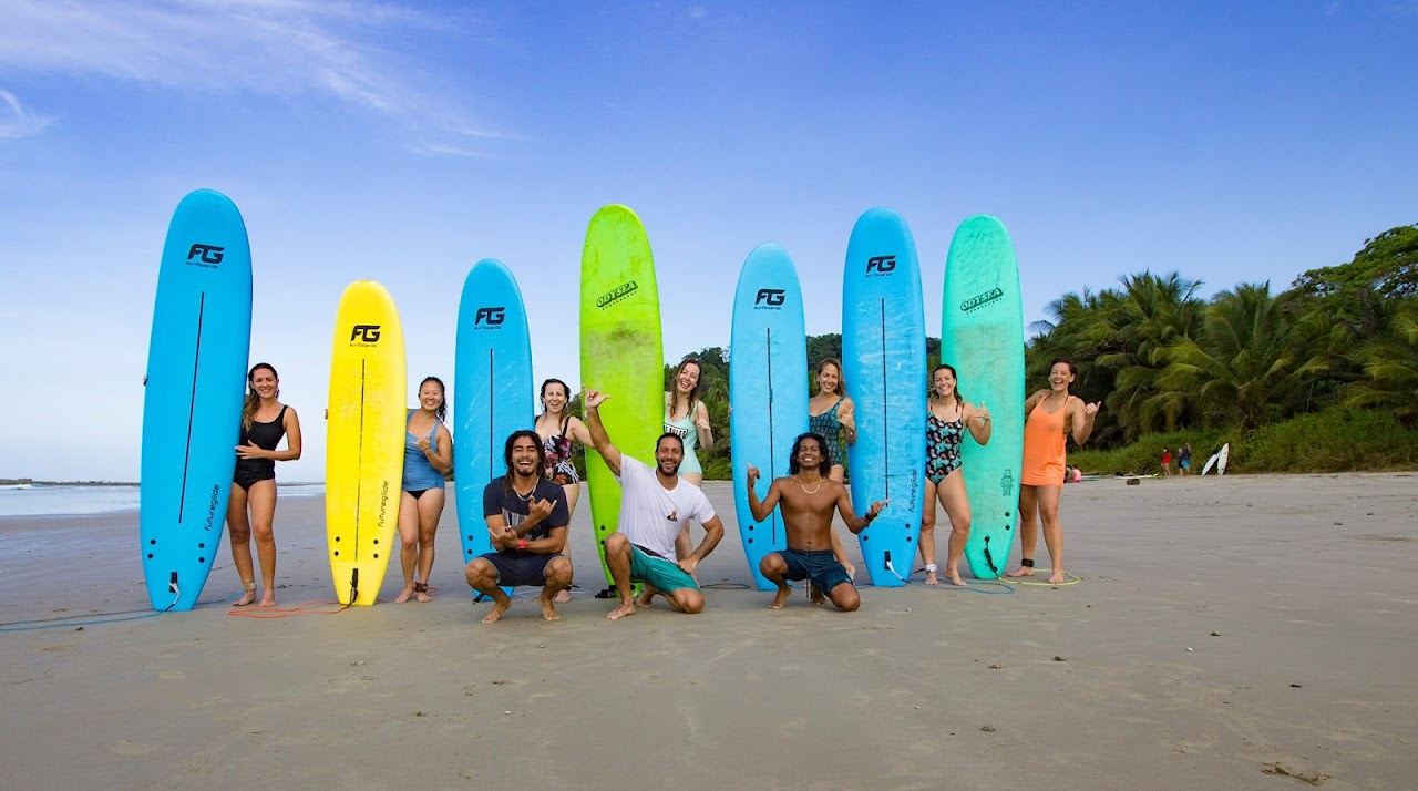 Surfers and golden sunset light on the wide sand of Playa Santa Teresa in Costa Rica