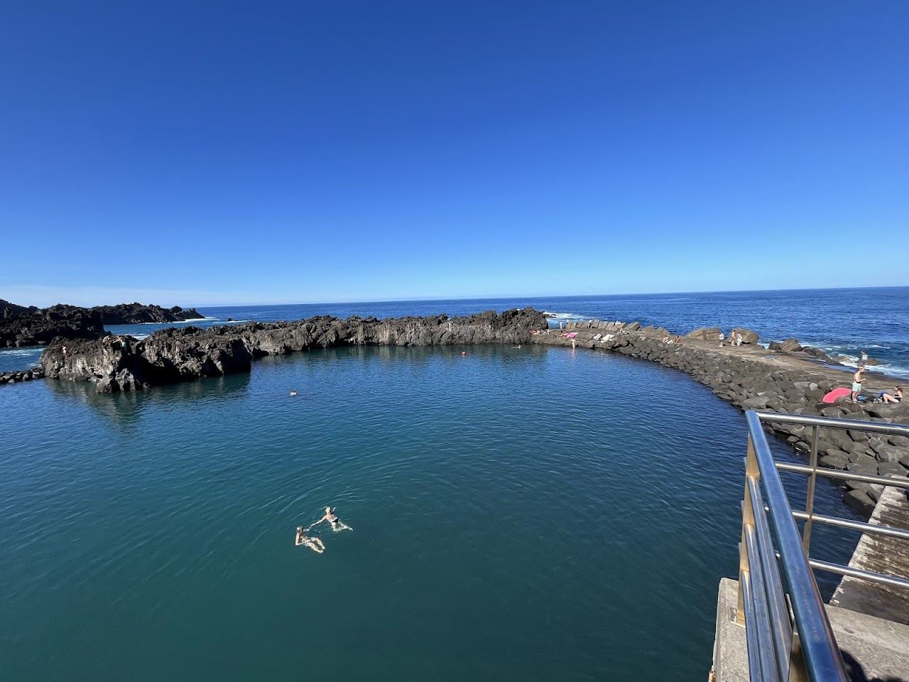 Dramatic black volcanic sand and a natural pool below green cliffs at Seixal on the north coast of Madeira