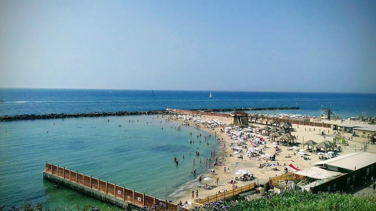 Metzitzim beach in Tel Aviv with bathers on golden sand beside the port breakwater