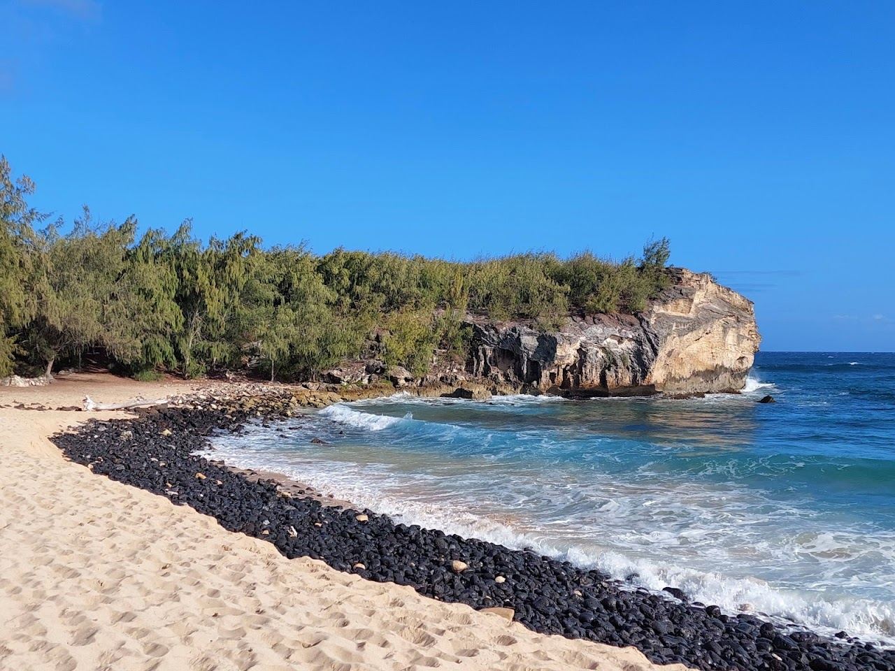 The wide golden sand and cliff of Shipwreck Beach at Keoneloa Bay in Poipu on Kauai