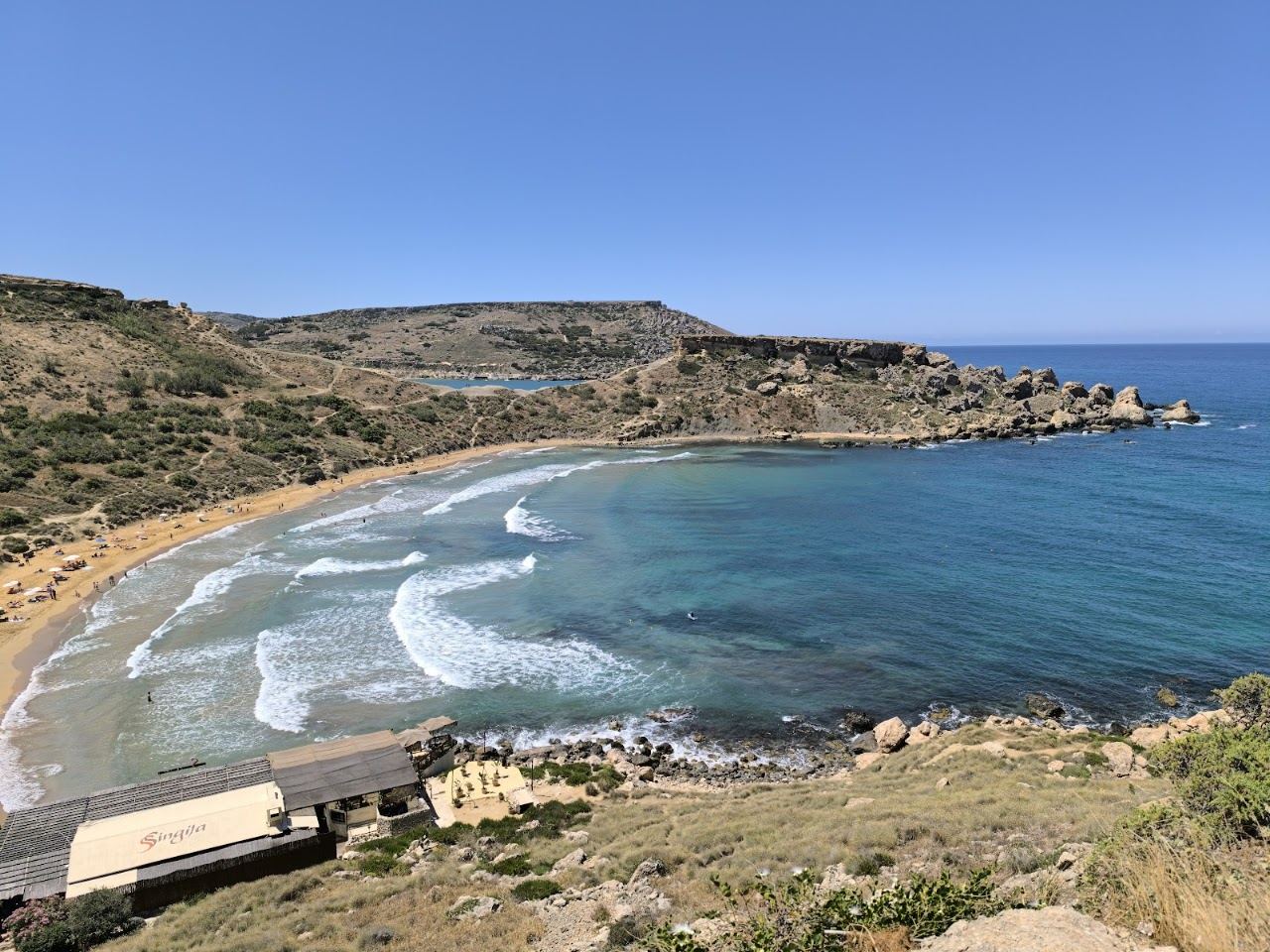 Reddish sand and clay slopes of Ghajn Tuffieha Bay seen from the clifftop path, Malta