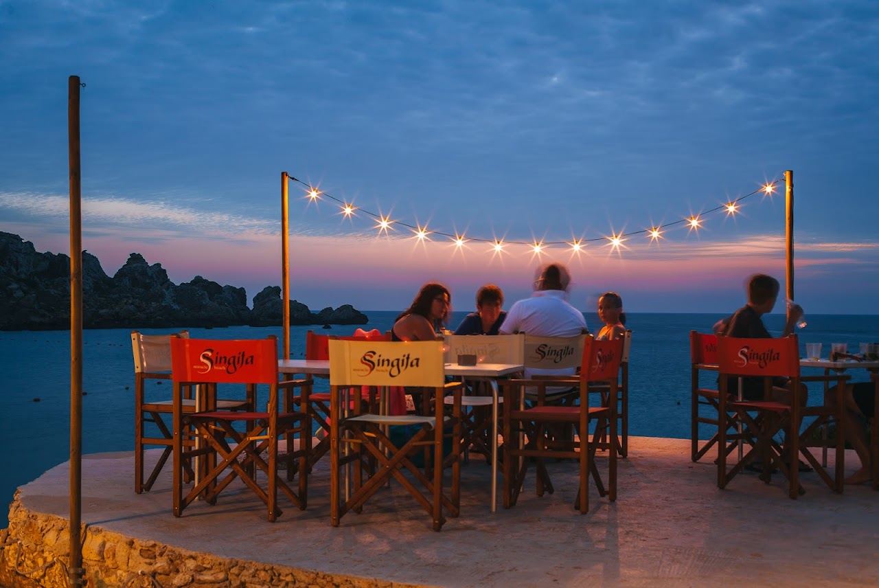 Straw umbrellas and sunbeds of Singita Miracle Beach on the sand of Ghajn Tuffieha Bay, Malta