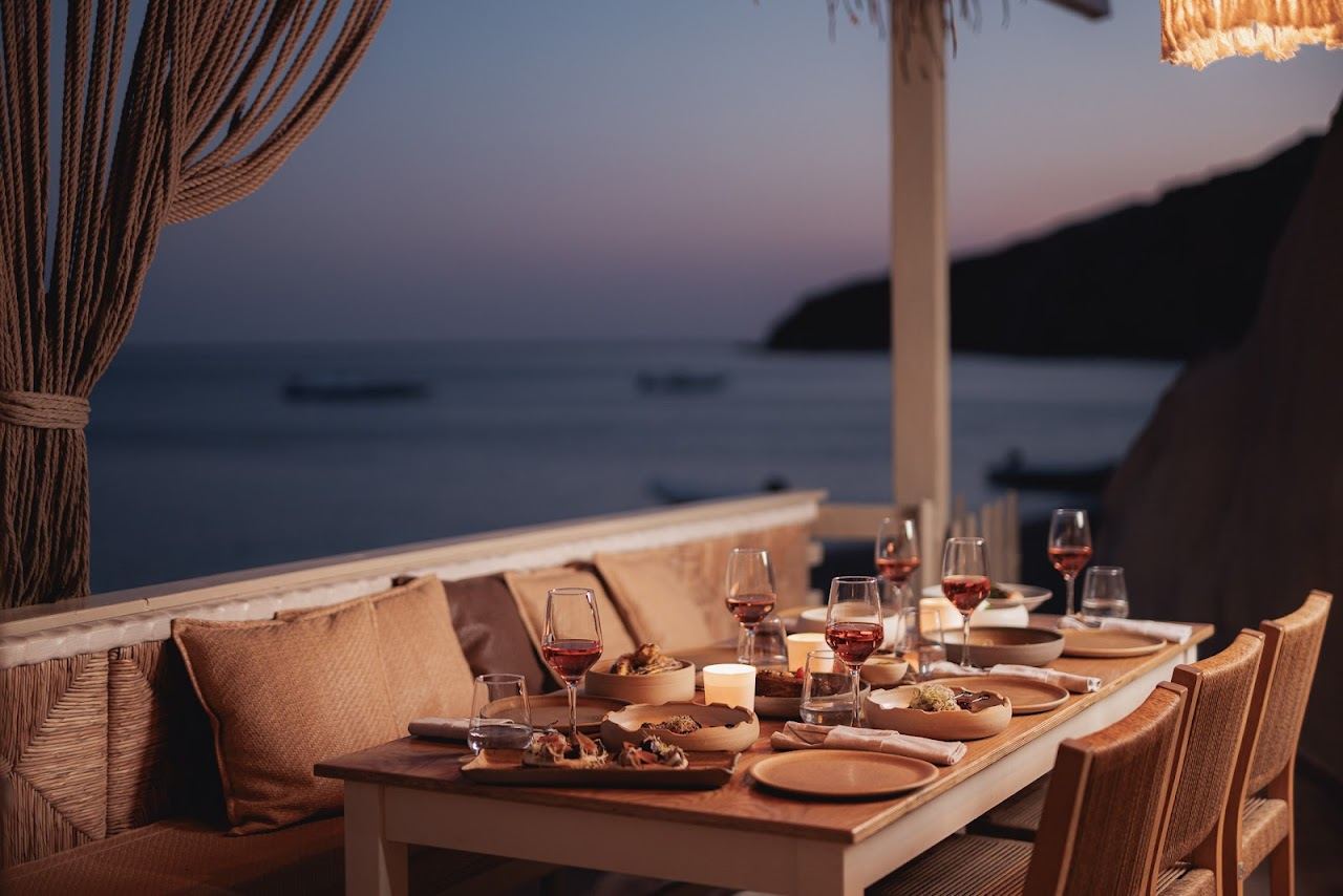 Tables of the Sirocco restaurant terrace on the volcanic sand of Paliochori beach in Milos
