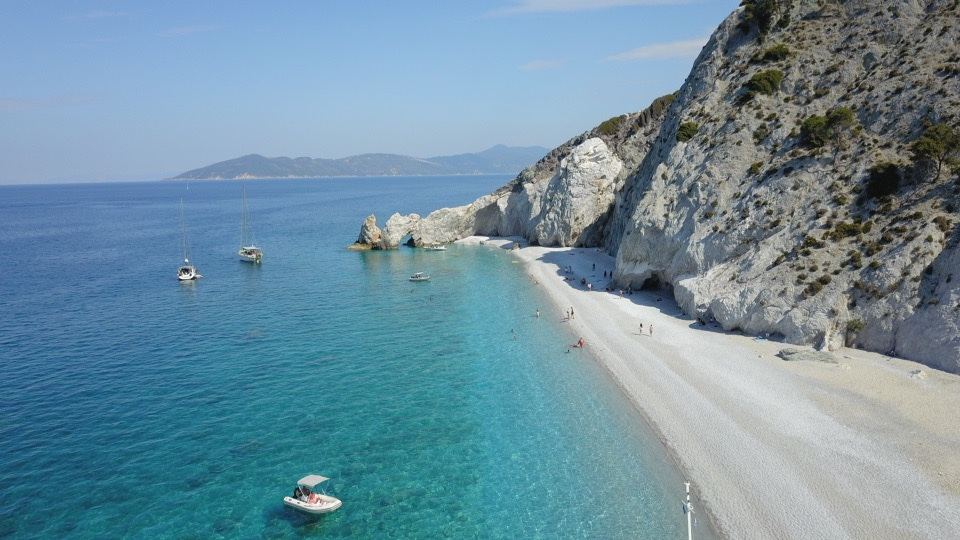 The white pebbles, cliffs and clear water of Lalaria cove on Skiathos, a romantic boat only swim for two
