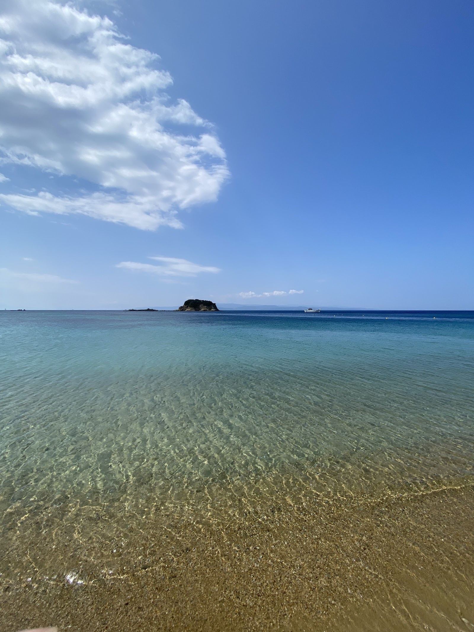 The gentle shallow water and golden sand of Troulos beach on the south coast of Skiathos