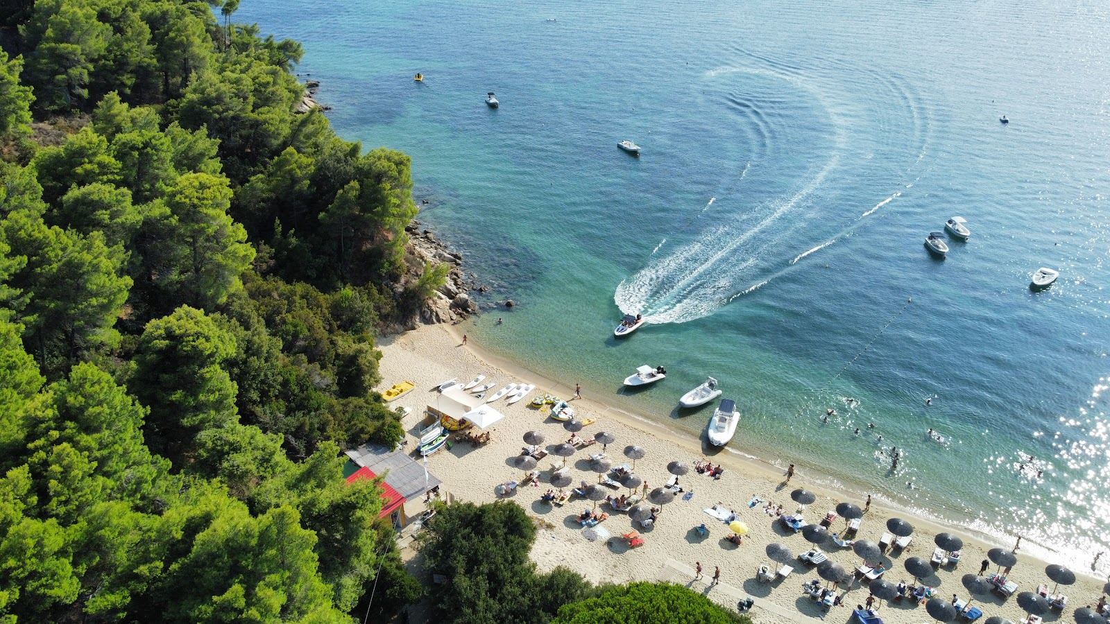 A boat and clear water off a lively south coast watersports beach on Skiathos