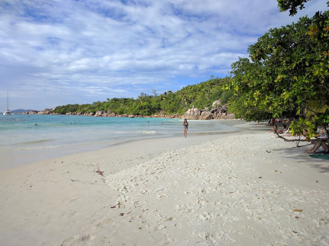 Clear water over granite and reef beside the pale sand of a Seychelles beach