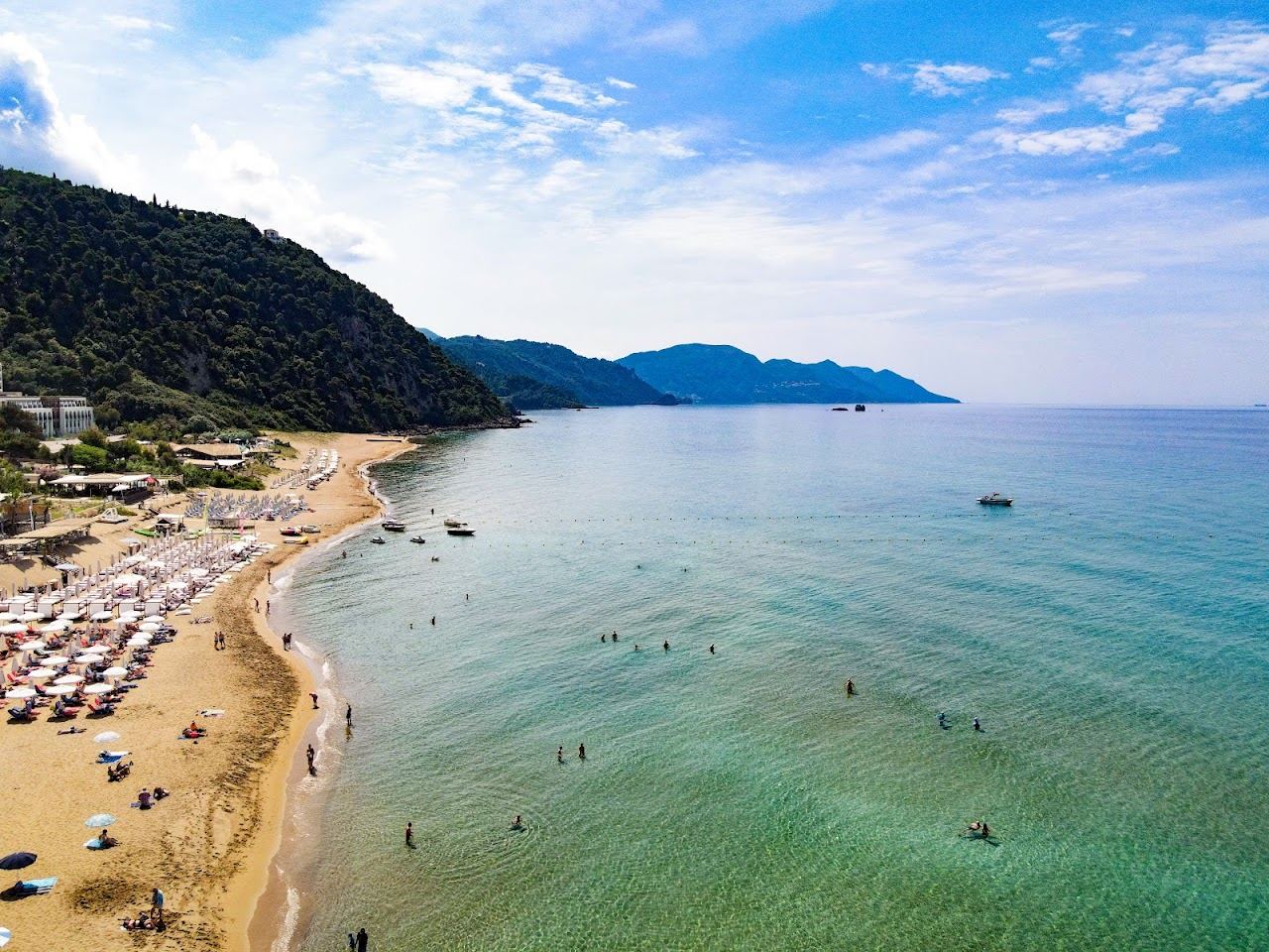 Golden sand and clear Ionian water at Glyfada beach in Corfu, the shore Sora Beach Club occupies