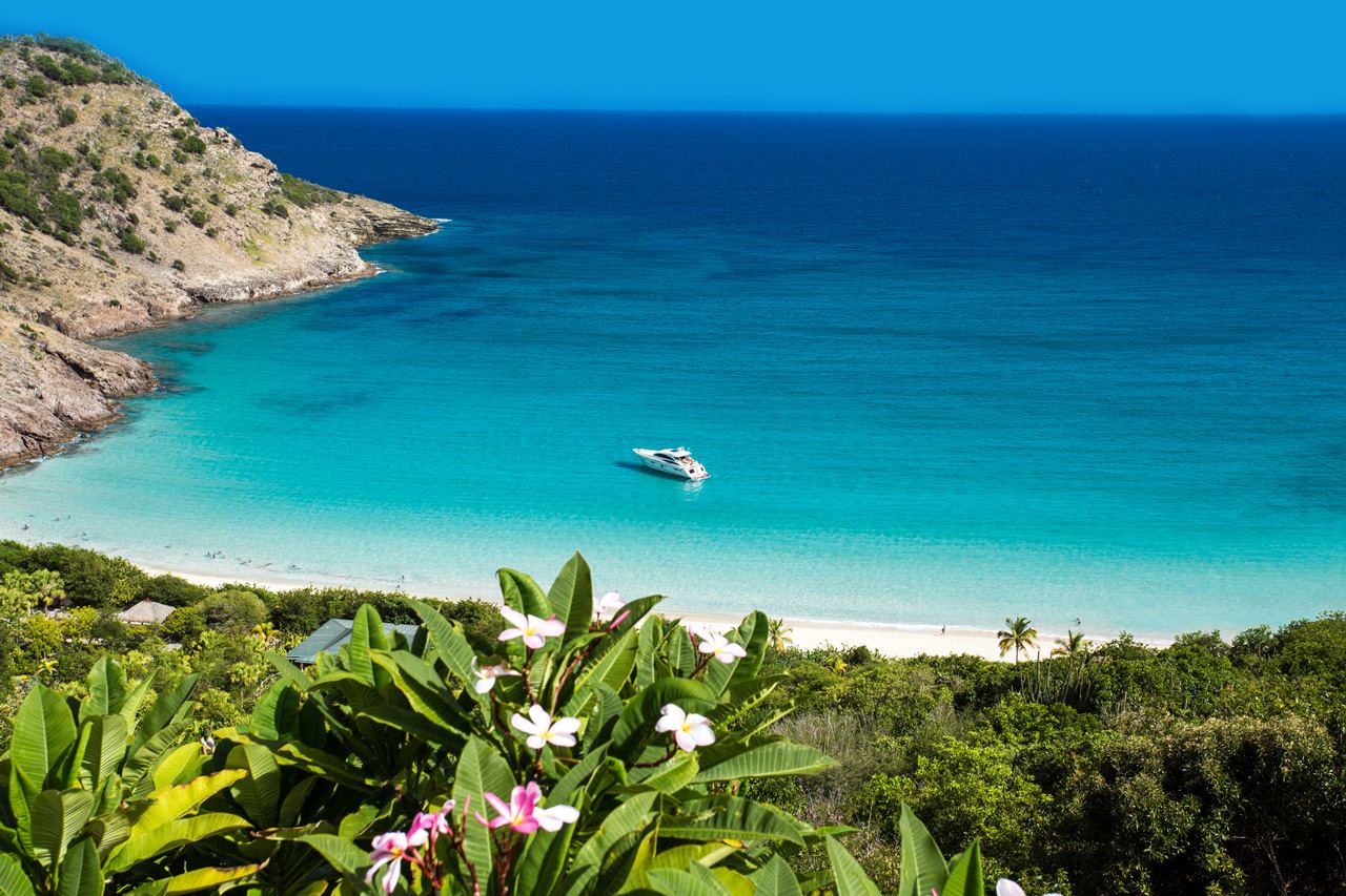 A wide undeveloped cove of pale sand between green headlands at Gouverneur on St Barths used for the beaches for couples guide on Beaches for Kings