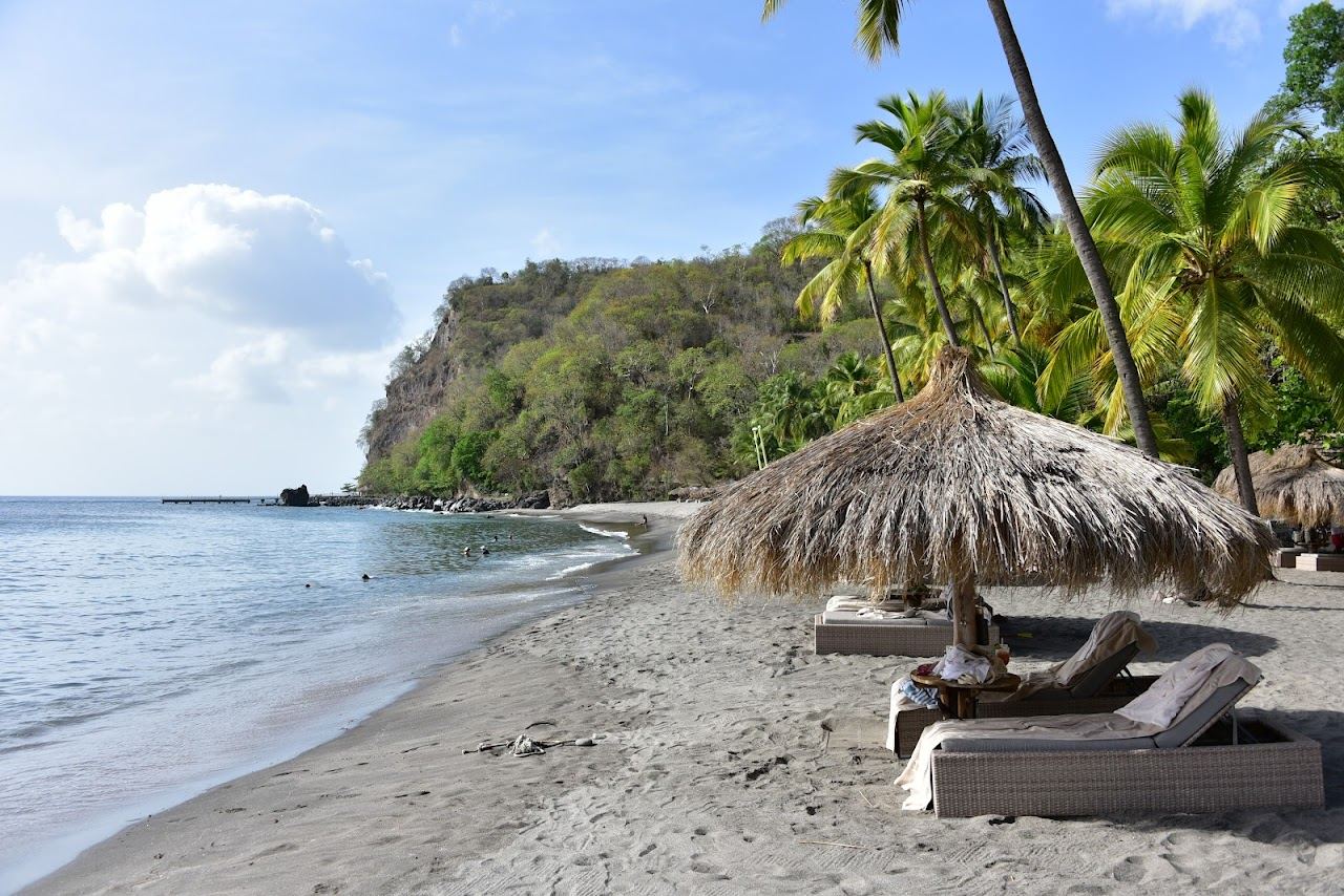 Calm clear water and dark volcanic sand framed by green hills at Anse Chastanet near Soufriere in St Lucia