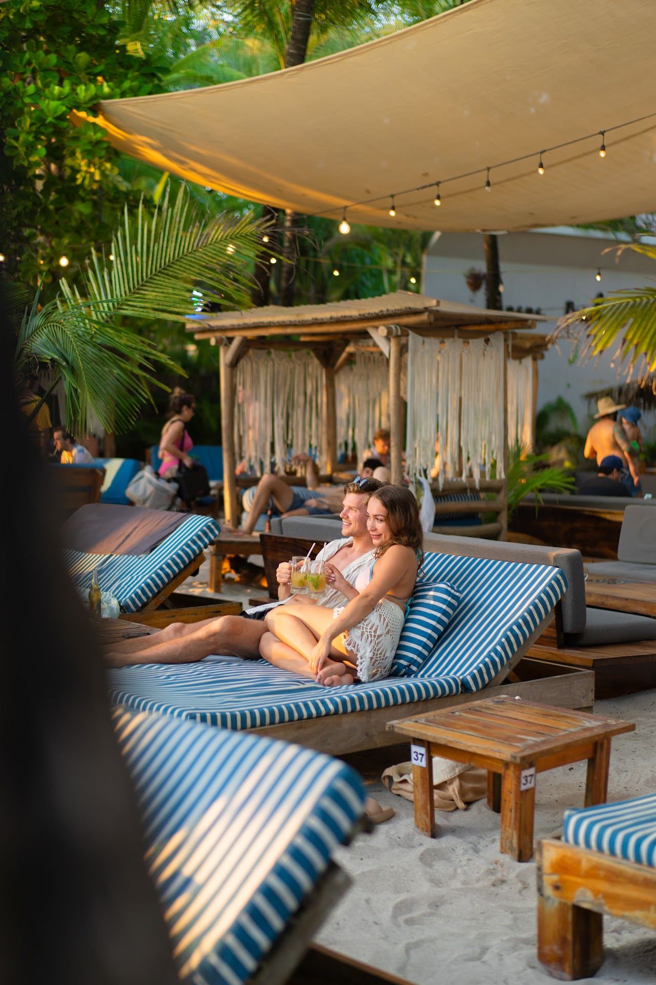 A lively beach bar with tables and palms on the sand at sunset in Santa Teresa Costa Rica