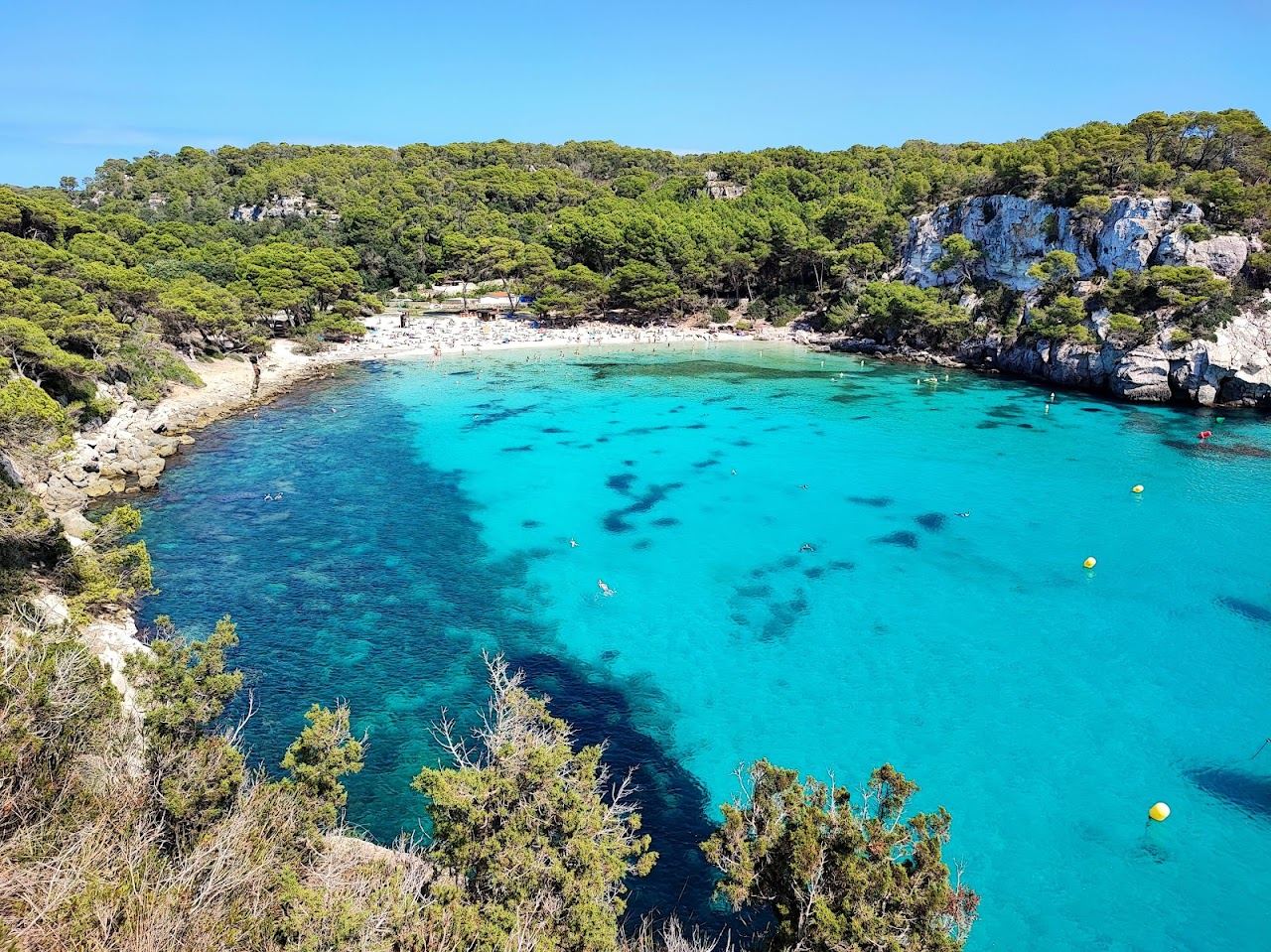 White sand and clear turquoise shallows of Cala Macarella seen from the water line in Menorca