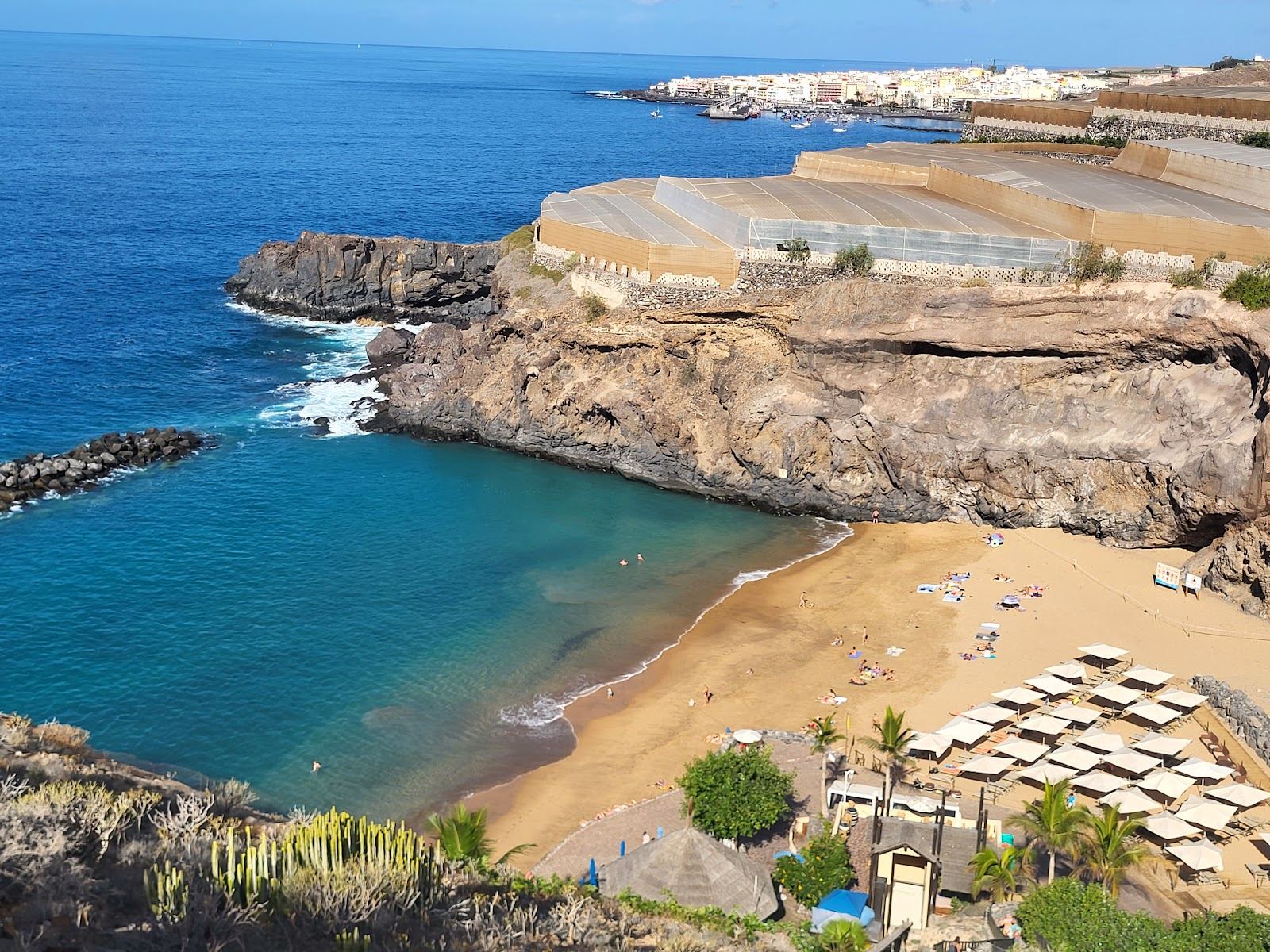 The sheltered cove and clear water of Playa de Abama on the southwest coast of Tenerife, backed by cliffs and palms