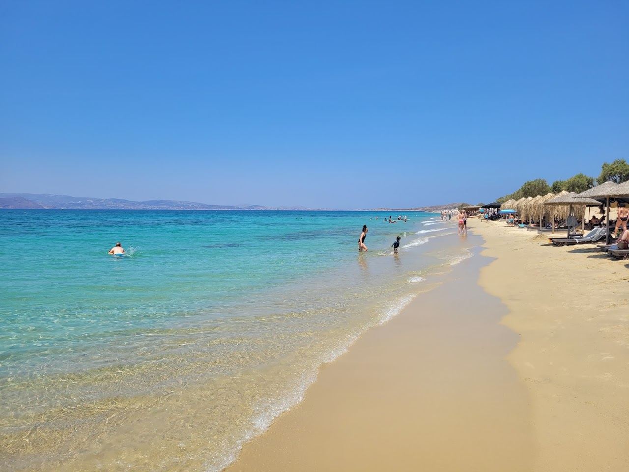 White sand and calm shallow water stretching along Plaka beach on Naxos