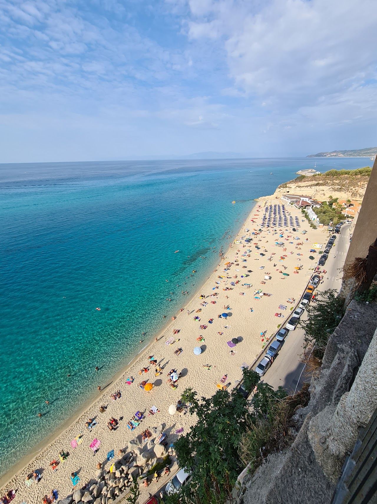The Tropea town beach seen from above, white sand and clear water below the sandstone cliff of the old town