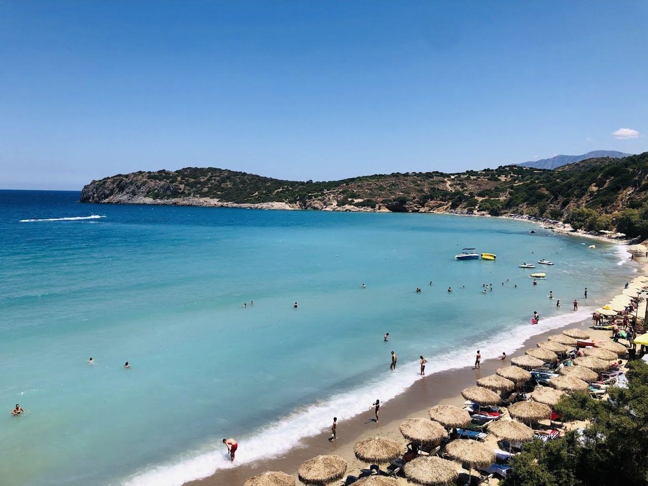 View over the golden sand and clear shallow bay of Voulisma beach with hills behind near Istron in east Crete