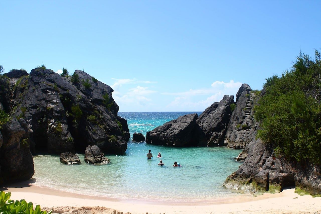 The wide open pink sand of Warwick Long Bay with low dunes and a limestone stack offshore in Bermuda