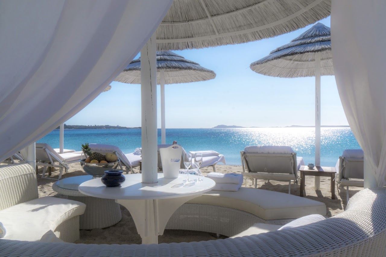 White loungers and umbrellas of White Beach Club on the pale sand of Liscia Ruja, Costa Smeralda