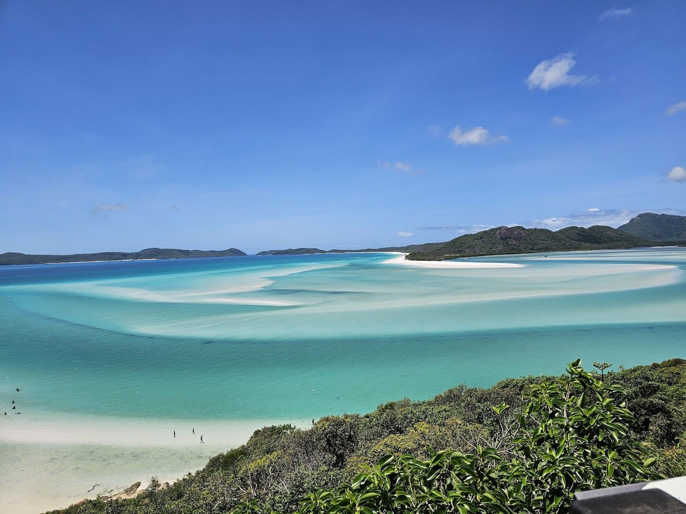 A quiet boulder dotted cove with clear water at Betty Beach on Whitsunday Island in the Whitsundays