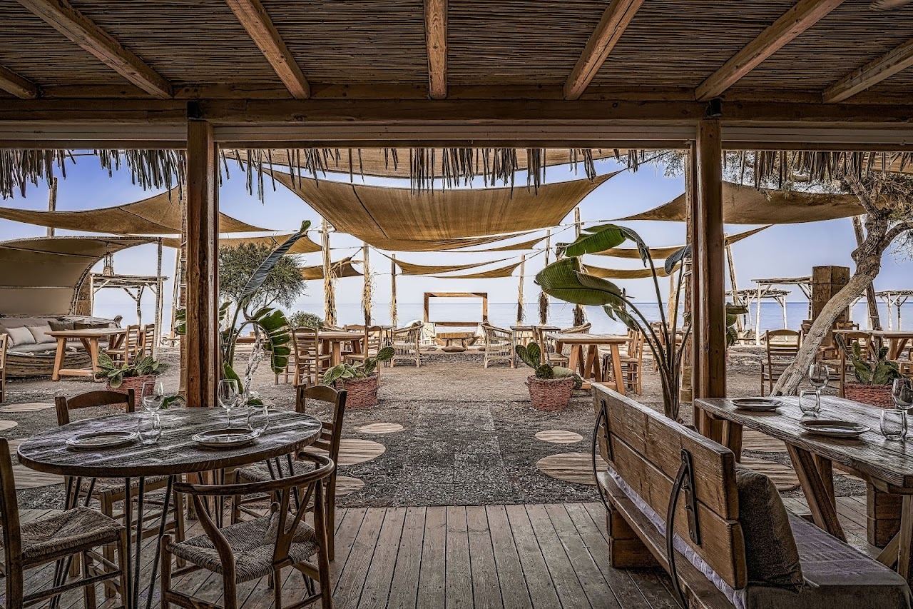 Driftwood styled sunbeds and cabanas on the calm Exo Gialos cove at Yalos beach bar under Fira in Santorini